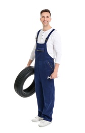 Male mechanic with car tire on white background