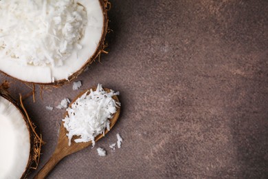 Photo of Coconut flakes in nut shell and spoon on brown table, flat lay. Space for text