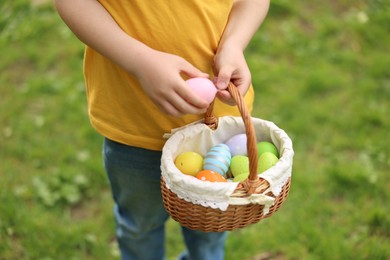 Easter celebration. Little boy holding basket with painted eggs outdoors, closeup