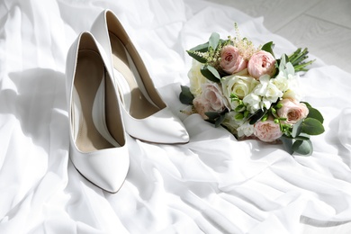 Photo of Pair of wedding high heel shoes and beautiful bouquet on white fabric