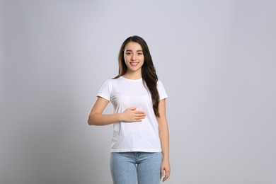 Photo of Happy healthy woman touching her belly on light grey background