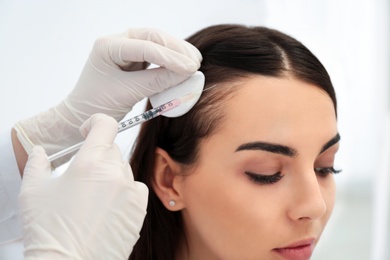 Photo of Young woman with hair loss problem receiving injection in salon