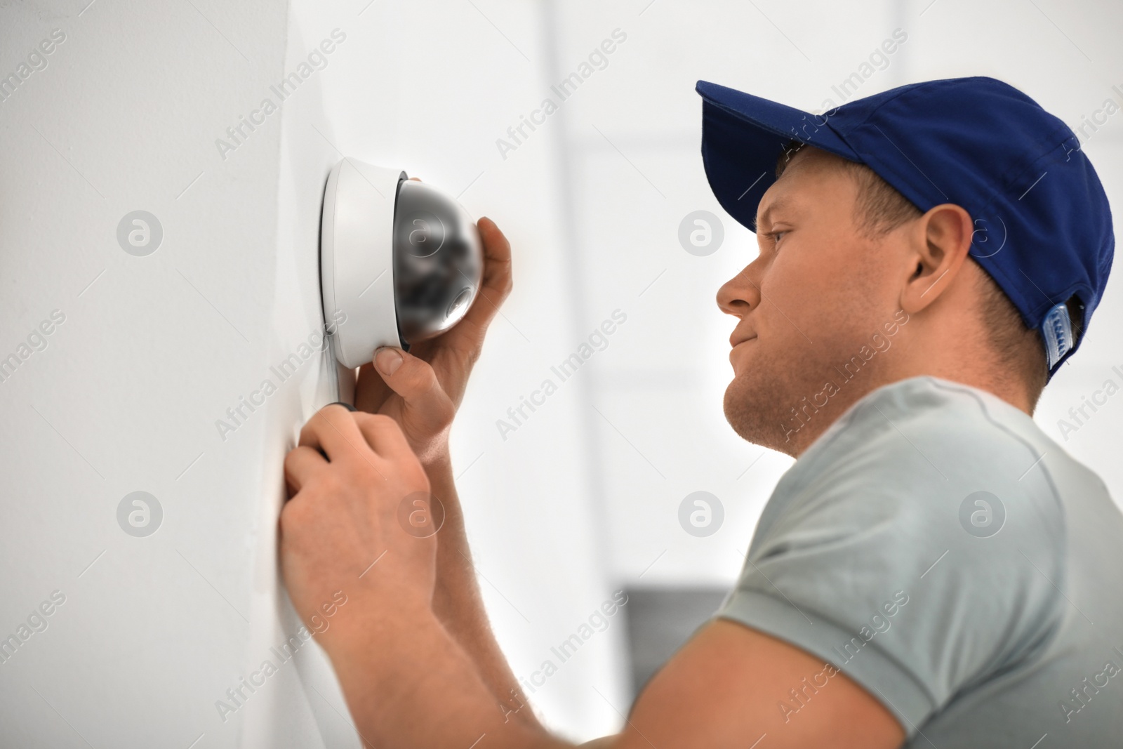 Photo of Technician installing CCTV camera on wall indoors