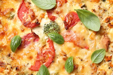 Photo of Tasty quiche with cheese, tomatoes and basil leaves as background, top view