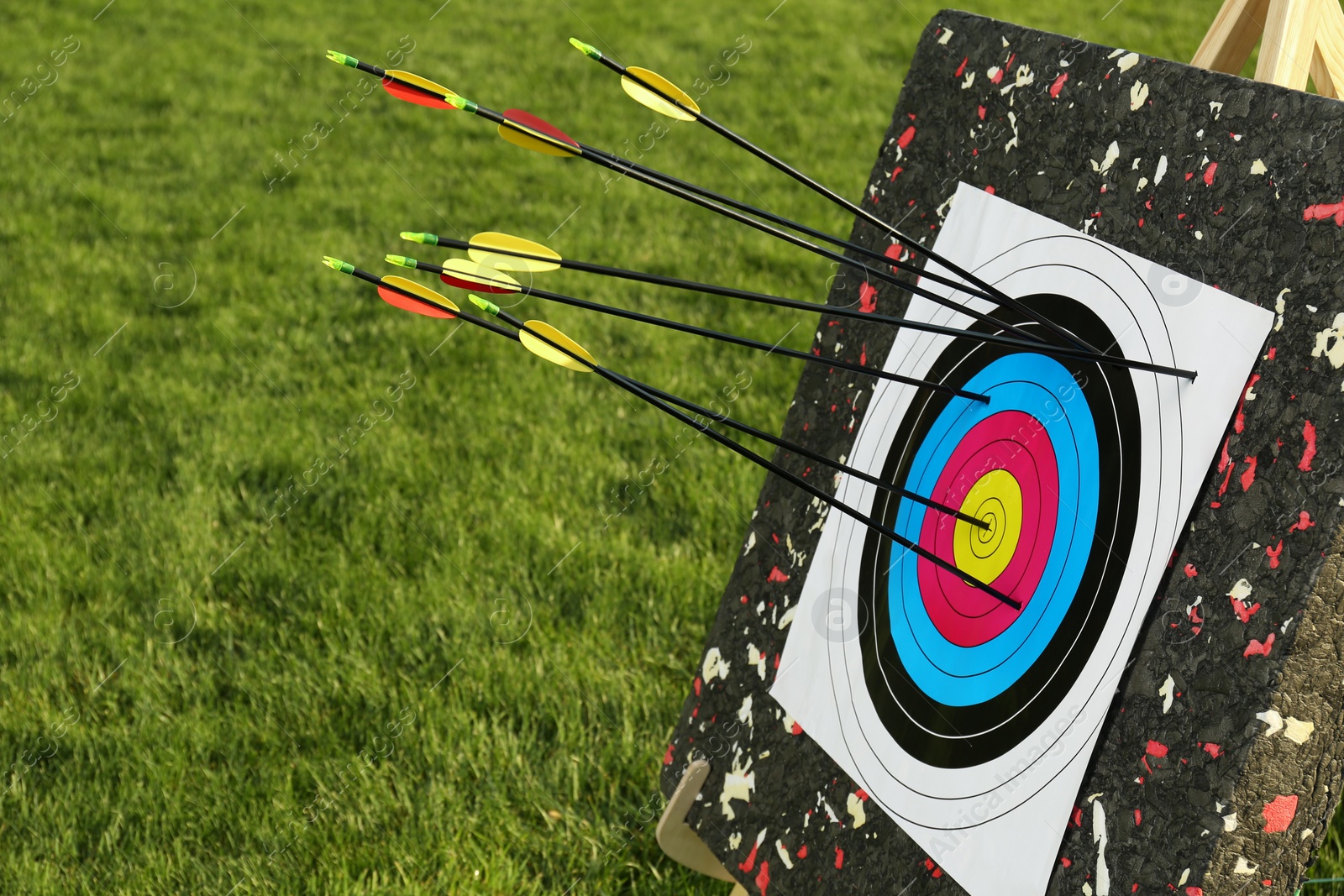 Photo of Arrows in archery target on green grass outdoors