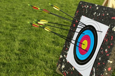 Photo of Arrows in archery target on green grass outdoors