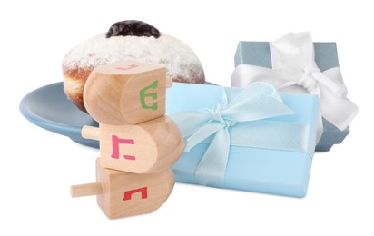 Photo of Hanukkah celebration. Wooden dreidels with jewish letters, gift boxes and donut isolated on white