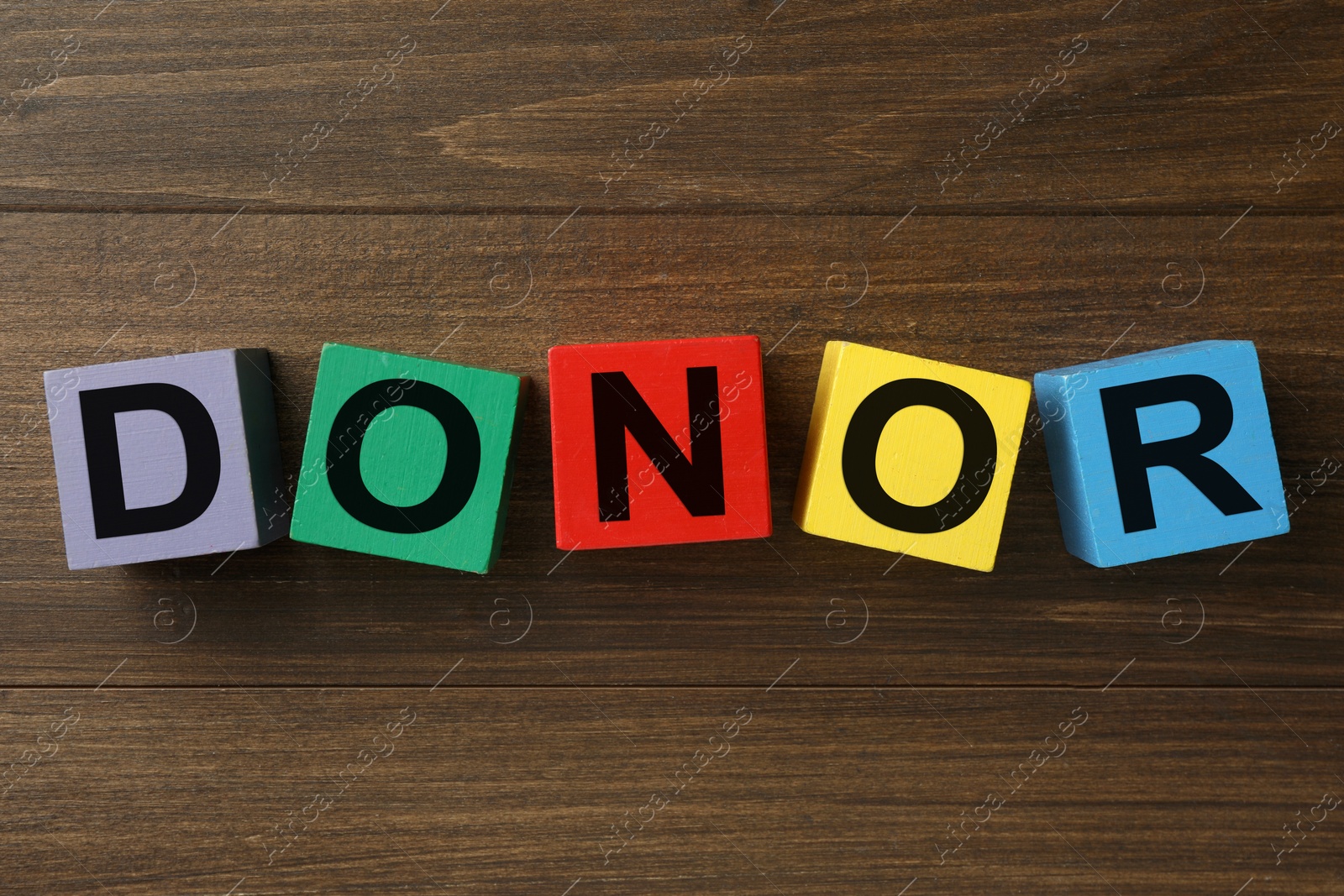 Photo of Word Donor made of colorful cubes on wooden table, top view