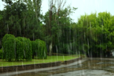 Blurred view of heavy pouring rain in green park