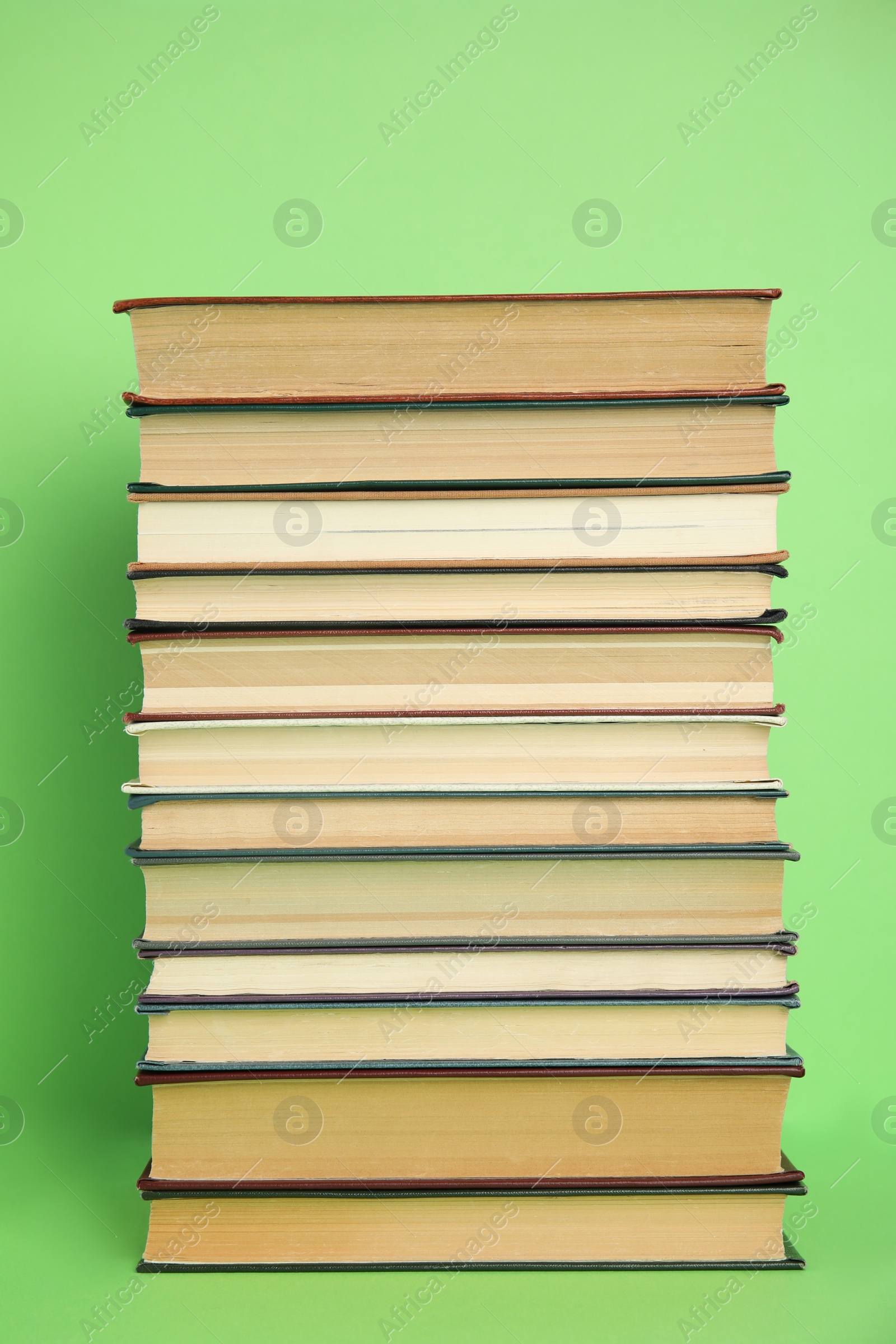Photo of Stack of different hardcover books on green background