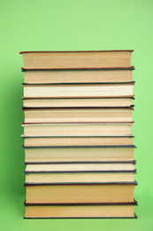 Stack of different hardcover books on green background