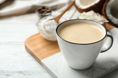 Photo of Delicious coffee with organic coconut oil on white wooden table