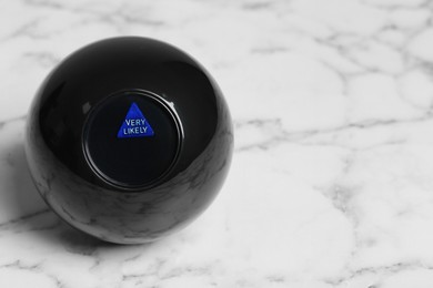 Photo of Magic eight ball with prediction Very Likely on white marble table, space for text