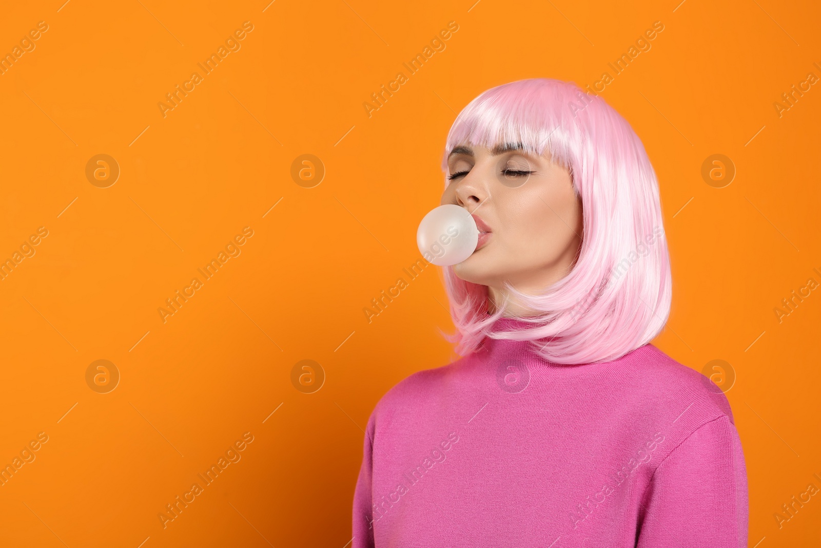 Photo of Beautiful woman blowing bubble gum on orange background, space for text