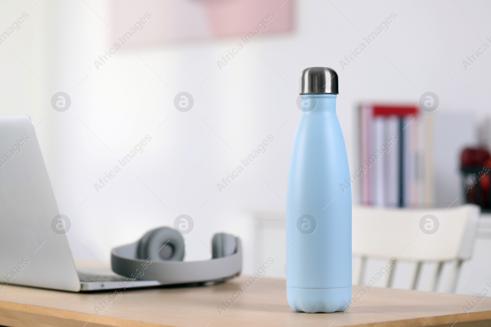 Photo of Stylish thermo bottle and laptop on wooden table at home. Space for text