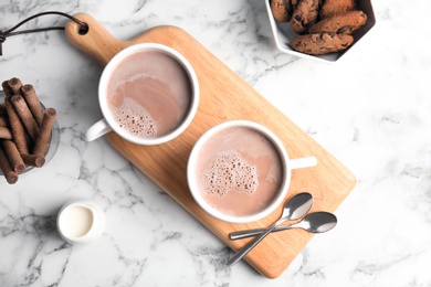 Flat lay composition with hot cocoa drink and cookies on marble table