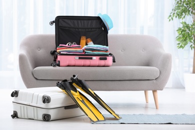 Modern suitcases packed for journey on sofa indoors