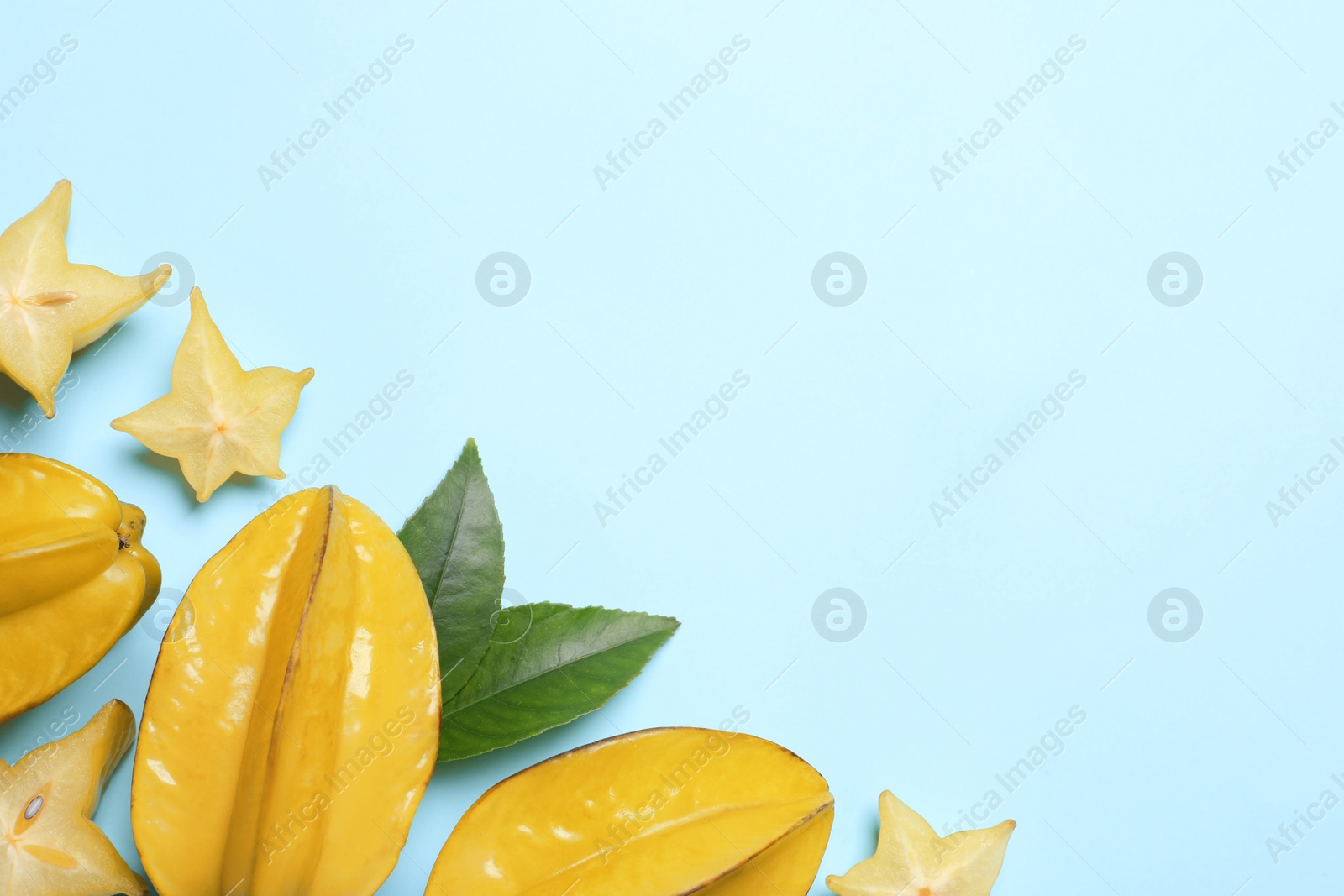 Photo of Delicious carambola fruits on light blue background, flat lay. Space for text