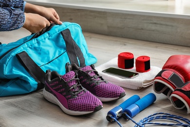 Young woman packing sports bag on floor