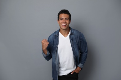 Photo of Happy handsome young African-American man on grey background