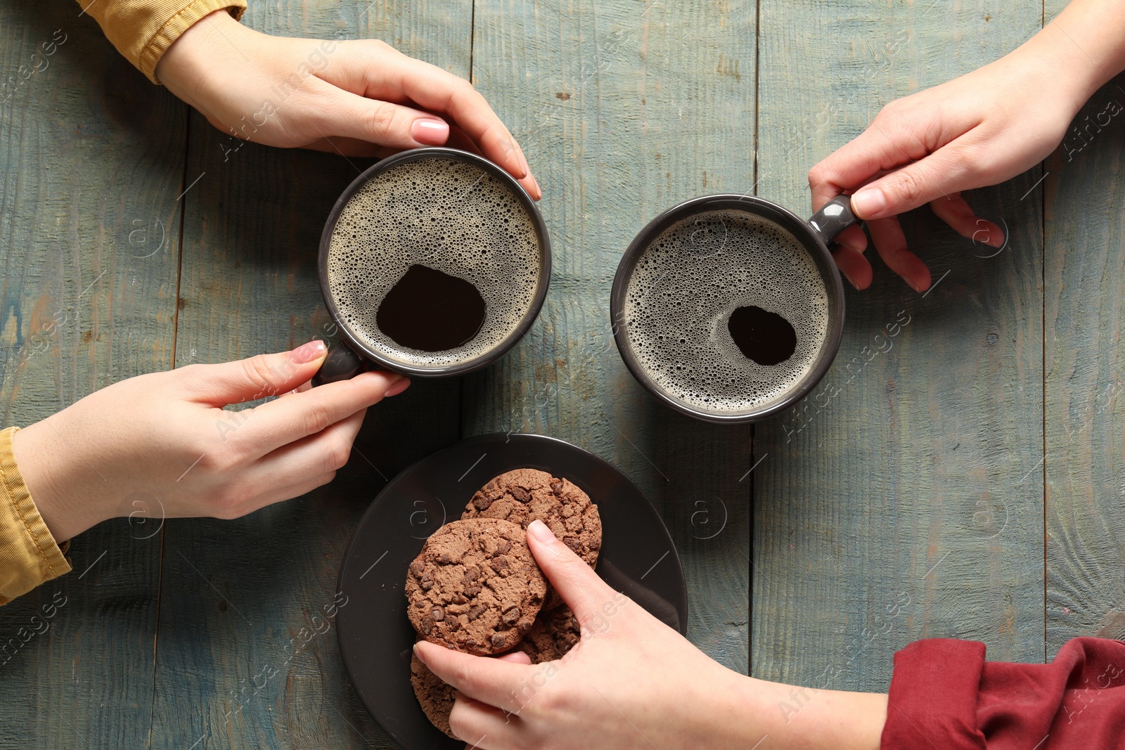 Photo of Women having coffee break at rustic wooden table, top view