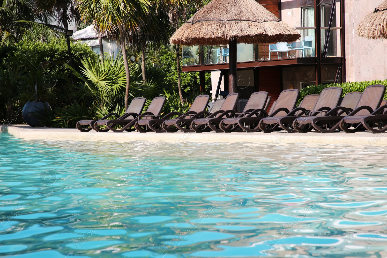 Photo of Outdoor swimming pool with sunbeds at resort on sunny day