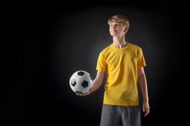 Photo of Teenage boy with soccer ball on black background. Space for text