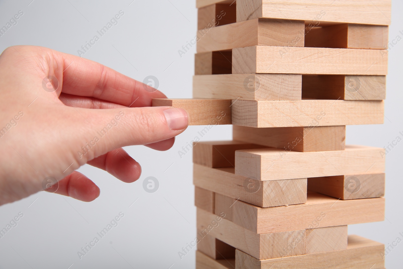 Photo of Woman playing Jenga on light gray background, closeup