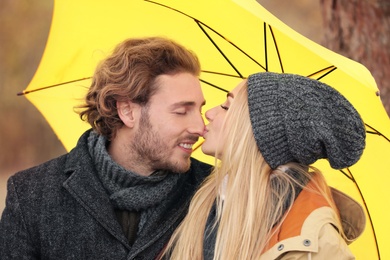 Young romantic couple with umbrella outdoors on autumn day