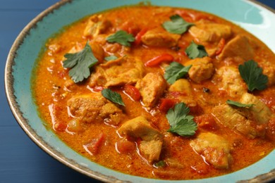 Photo of Delicious chicken curry on blue table, closeup