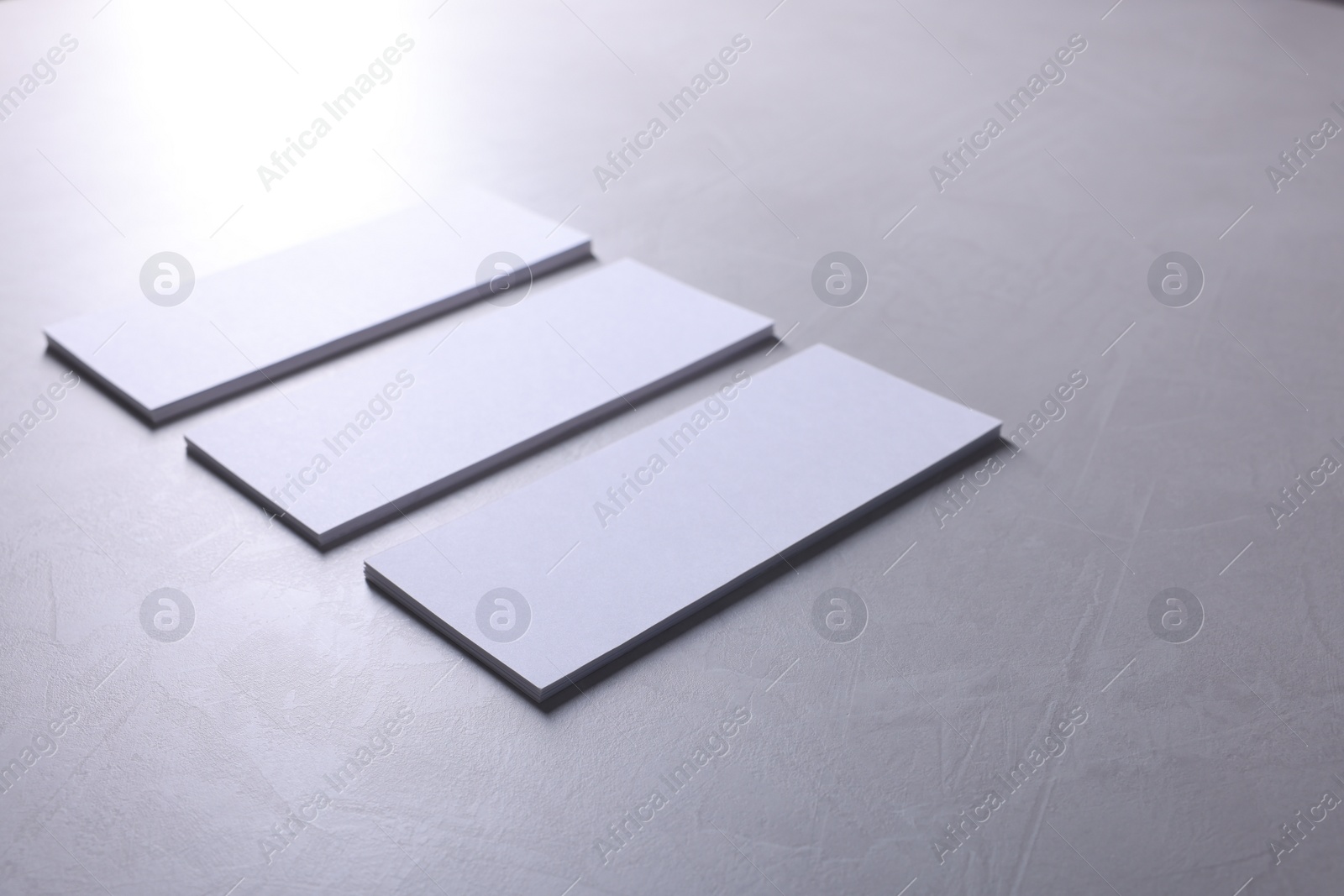 Photo of Blank business cards on light grey textured table, closeup. Mockup for design