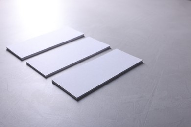 Blank business cards on light grey textured table, closeup. Mockup for design