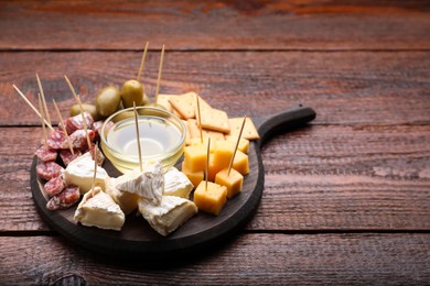 Toothpick appetizers. Pieces of cheese, sausage and honey on wooden table, space for text