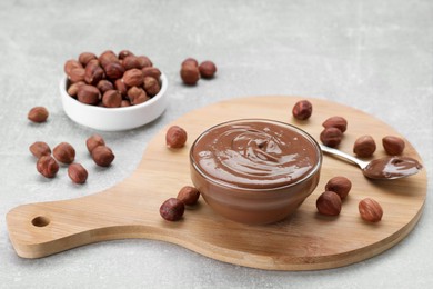 Bowl with tasty chocolate paste and nuts on light grey table