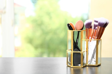 Photo of Organizer with makeup brushes on table. Space for text