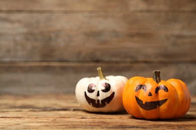 Photo of Pumpkins with scary faces on wooden background, space for text. Halloween decor