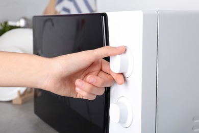 Woman adjusting microwave oven in kitchen, closeup