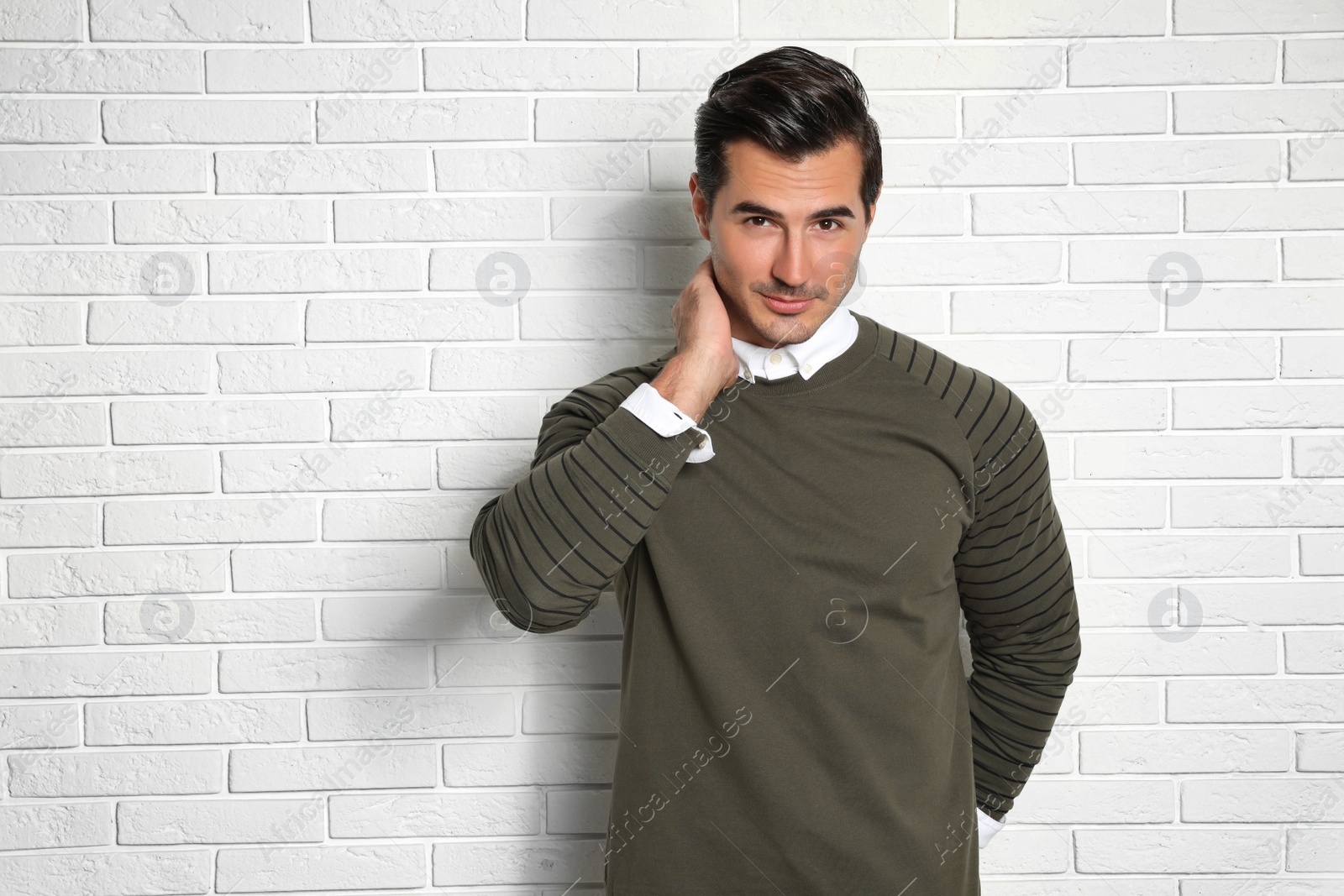 Photo of Portrait of handsome young man on white brick wall