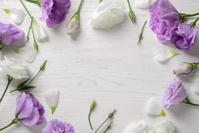 Photo of Flat lay composition with beautiful Eustoma flowers on light wooden background