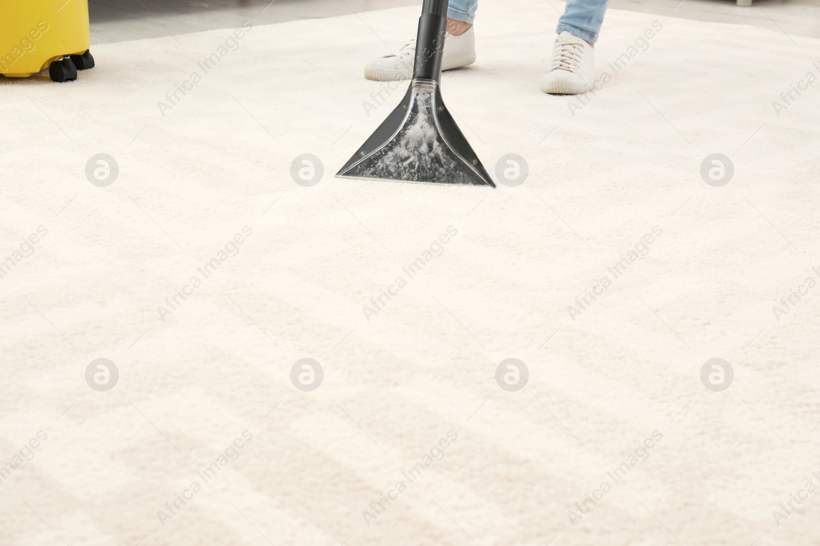 Photo of Woman removing dirt from carpet with vacuum cleaner indoors, closeup. Space for text