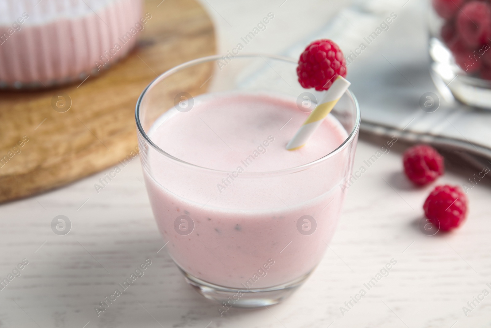 Photo of Tasty fresh milk shake with raspberry on white table, closeup