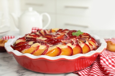 Delicious cake with plums on white marble table, closeup