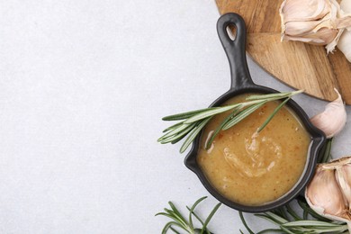 Delicious turkey gravy, rosemary and garlic on light grey table, flat lay. Space for text