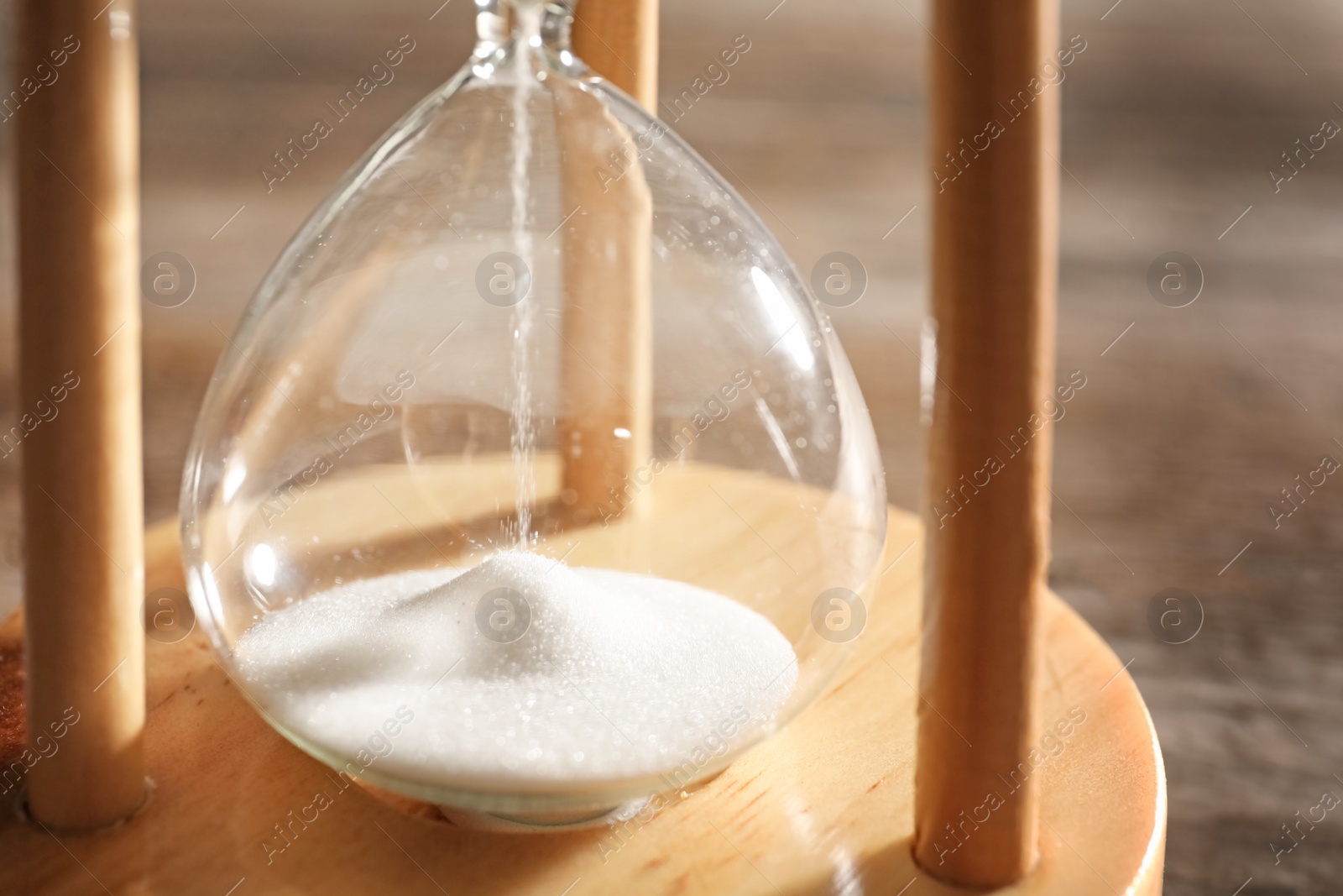 Photo of Hourglass with flowing sand on table, closeup. Time management