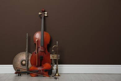 Photo of Set of different musical instruments near brown wall indoors, space for text
