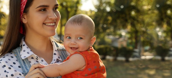 Happy mother with adorable baby in park on sunny day, space for text. Banner design 