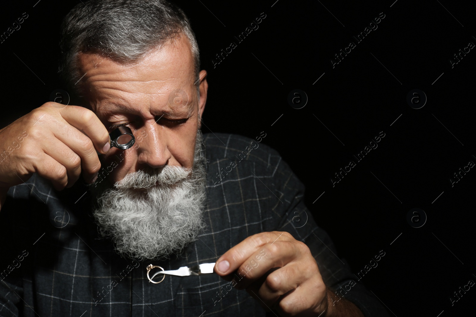 Photo of Male jeweler evaluating diamond ring in workshop, space for text