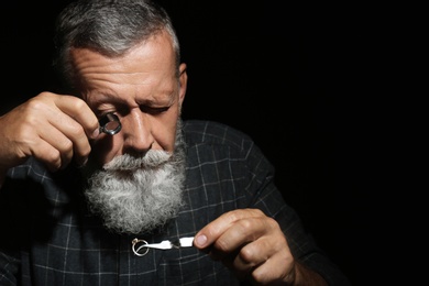 Male jeweler evaluating diamond ring in workshop, space for text