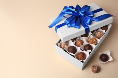 Photo of Box with delicious chocolate candies on beige background. Space for text
