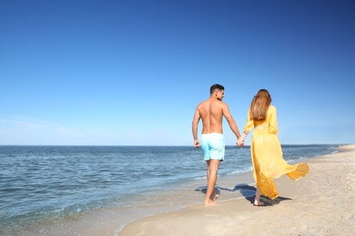 Photo of Woman in bikini and her boyfriend on beach, space for text. Lovely couple